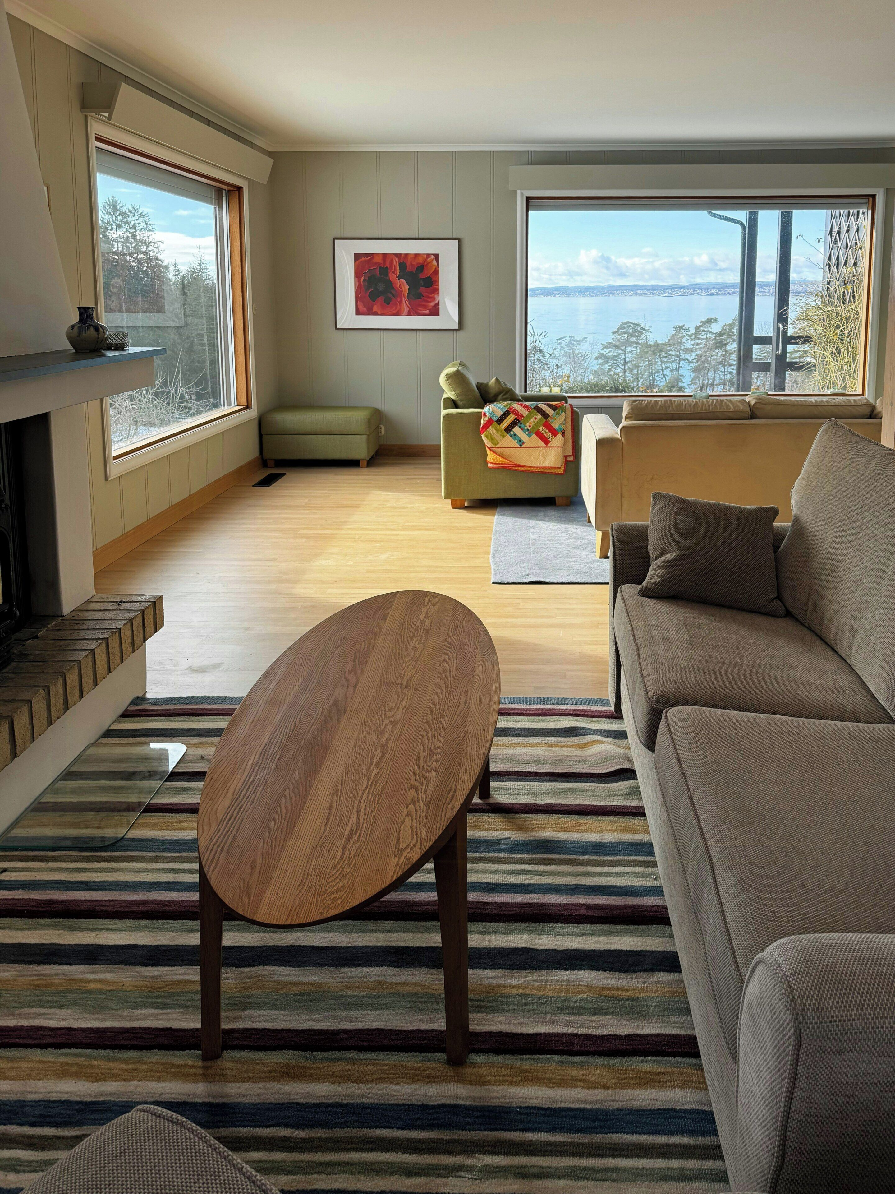 A living room with a sofa, a coffee table, a fireplace, and large windows.