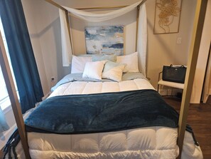 Ein Bett mit Baldachin, ein Nachttisch mit einer Handtasche und ein Gemälde an der Wand.