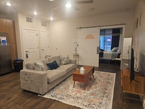Ein Wohnzimmer mit einer Couch, einem Couchtisch, einem gemusterten Teppich und einem Fernseher.