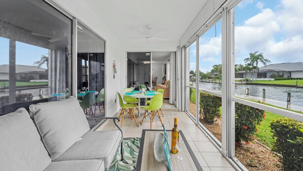 Un balcon équipé d’un canapé, d’une table à manger, de chaises et offrant une vue sur un plan d’eau.