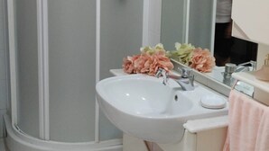 Ein Badezimmer mit Dusche, Waschbecken, Spiegel und Handtuchhalter.