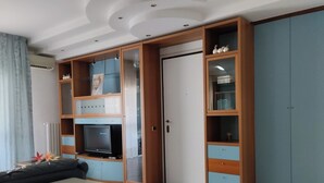 Ein Zimmer mit integriertem Fernseher, einem Schrank mit Glastüren und einer Kommode.