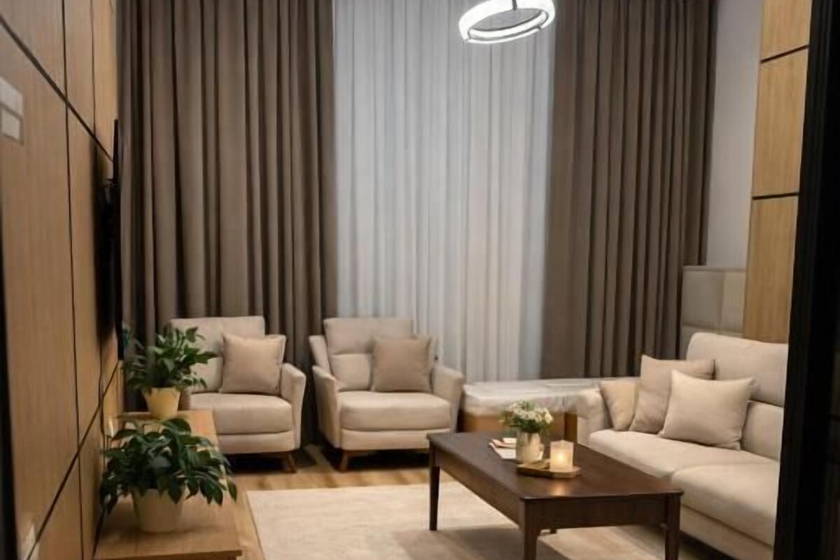 Un salon moderne avec un canapé, des fauteuils, une table basse et une plante en pot.