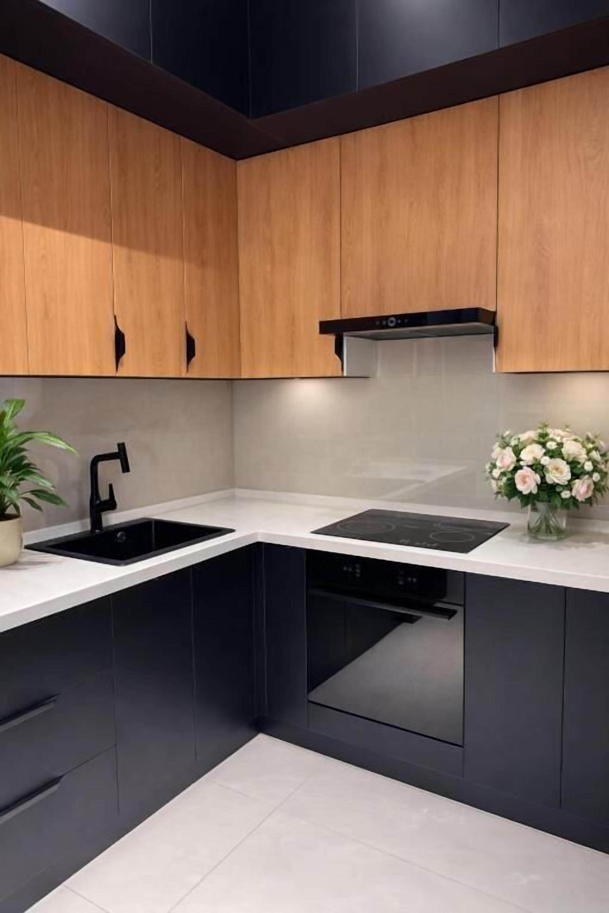 A modern kitchen with black cabinets, a white countertop, a built-in oven, and a black range hood.