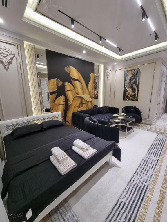 A modern hotel room with a large bed, a seating area, and a wall with abstract art.