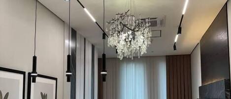 Una sala de estar moderna con un sofá, un comedor, lámparas colgantes y una araña.