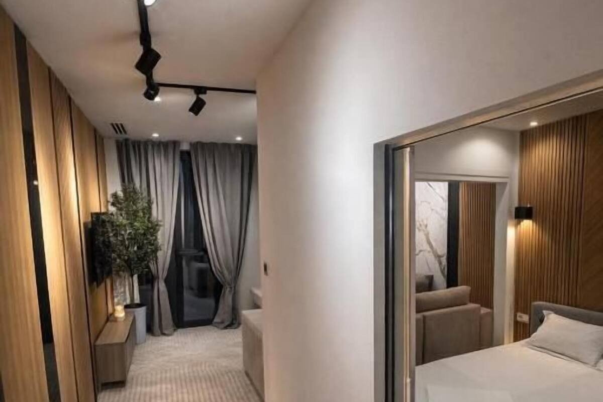 Una habitación de hotel moderna con una cama grande, un espejo, una mesita de noche y una planta.