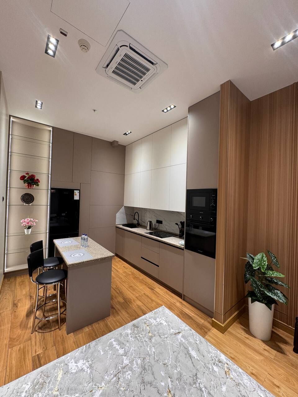 Eine moderne Küche mit einer zentralen Kochinsel, integrierten Geräten und einer Wand als Holzoptik.