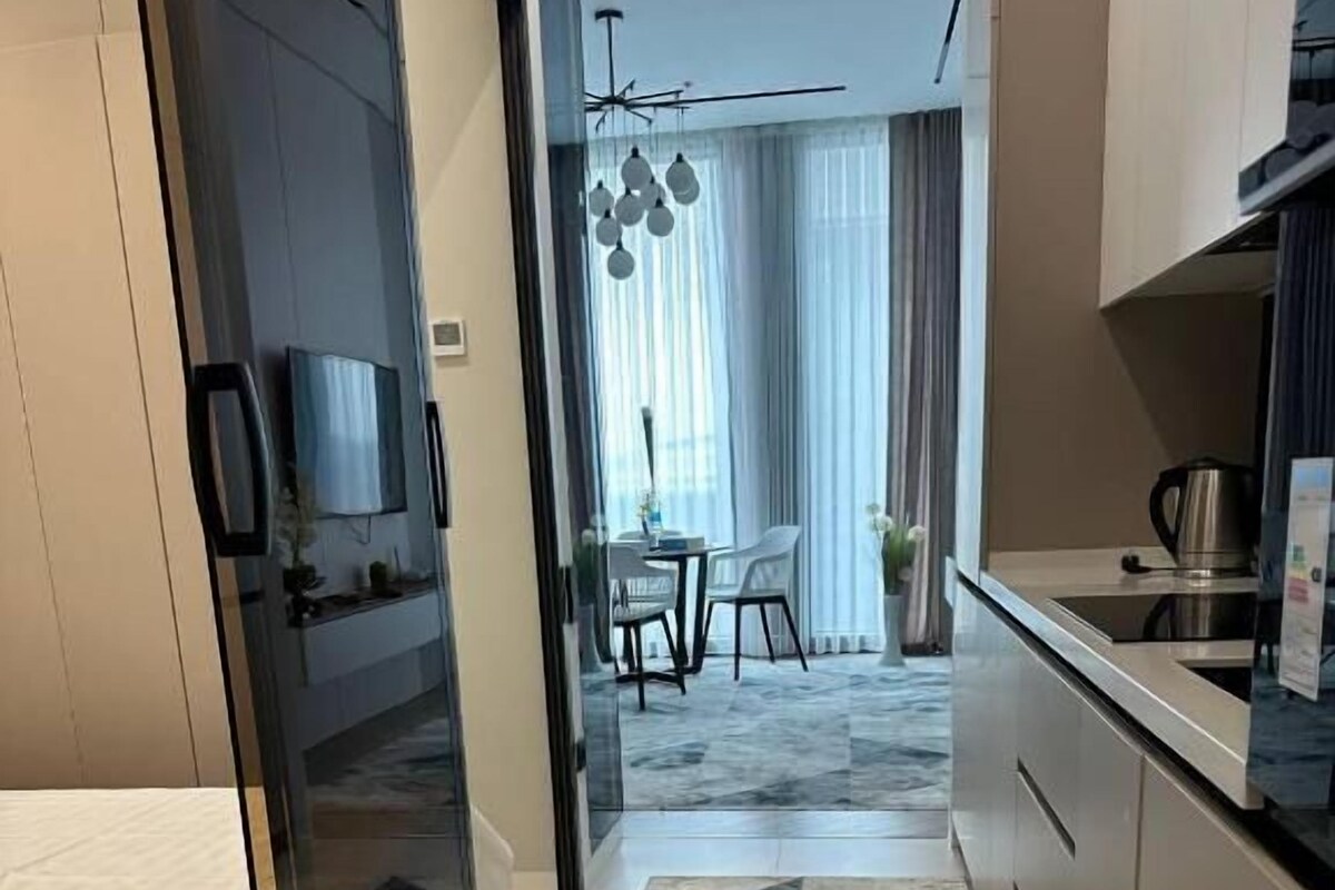 Une cuisine moderne avec un coin repas, un téléviseur et une vue sur un salon comprenant une table et des chaises.
