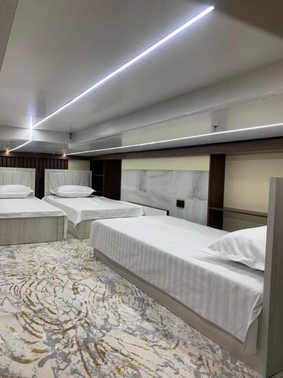 A hotel room with three beds, a marble headboard, and a patterned carpet.