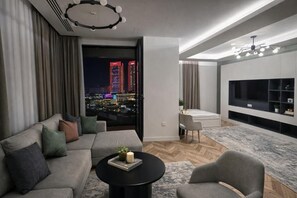 A modern living room with a sofa, armchair, coffee table, and a TV against a wall.