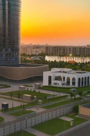 A modern building complex with a curved glass facade, a white building with arched windows, and a landscaped area with fountains. - Nestone - Apartment Hotels (Tashkent)