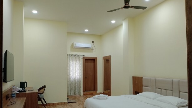 Ein Schlafzimmer mit Bett, Schreibtisch, Stuhl, Deckenventilator und Klimaanlage.