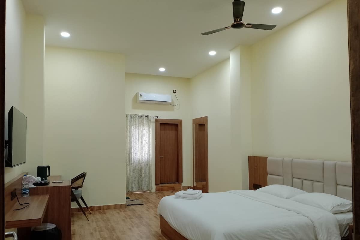Un dormitorio con cama, escritorio, silla, ventilador de techo y unidad de aire acondicionado.