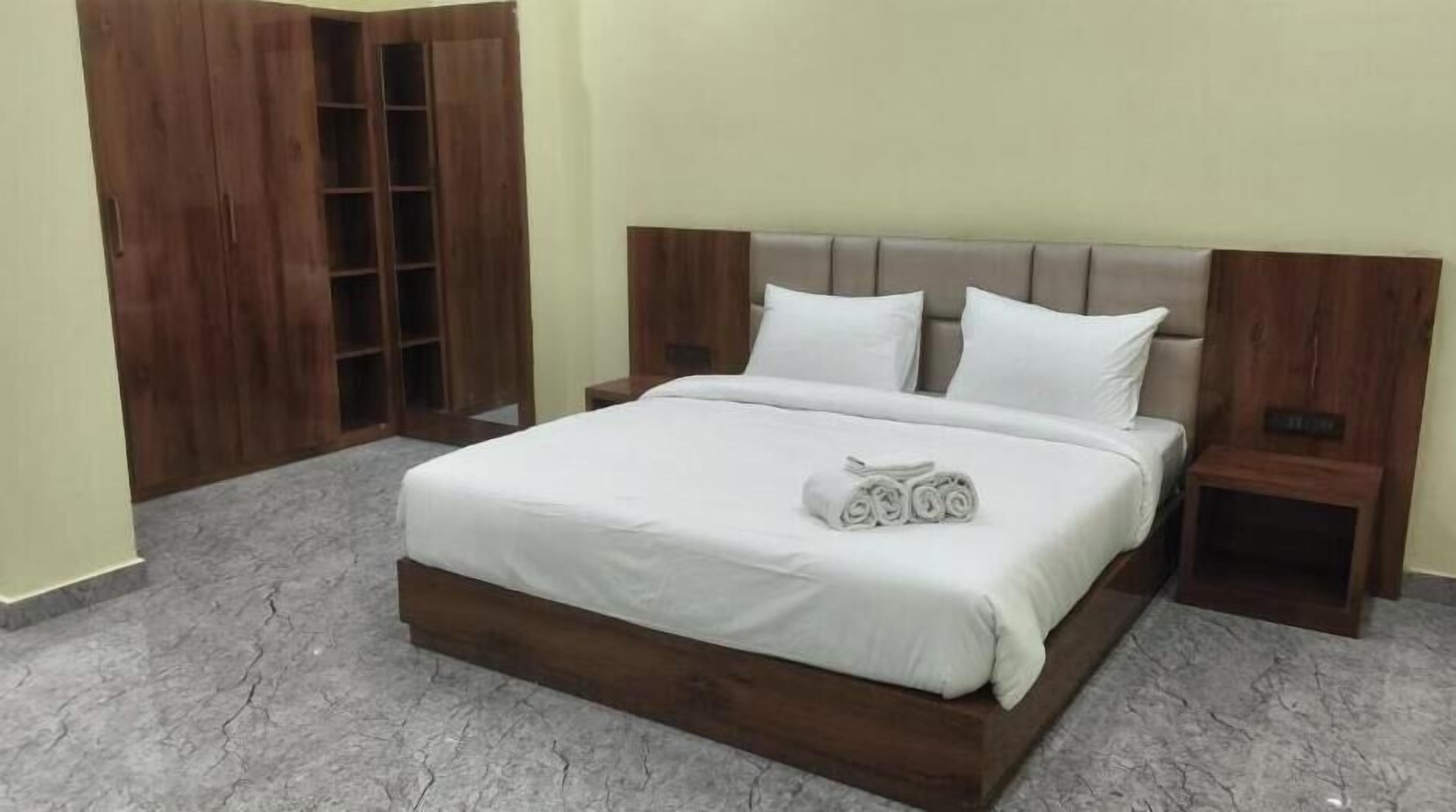 A bedroom with a bed, wooden wardrobe, and a nightstand.