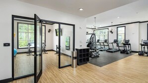 A modern gym with exercise equipment, large windows, and a yoga area. - Landing Apartments Charlotte near Bradfield Farms (Charlotte)