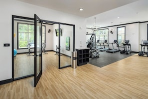 A modern gym with exercise equipment, large windows, and a yoga area. - Landing Beautiful 1bd, Game Room, Gym (Charlotte)