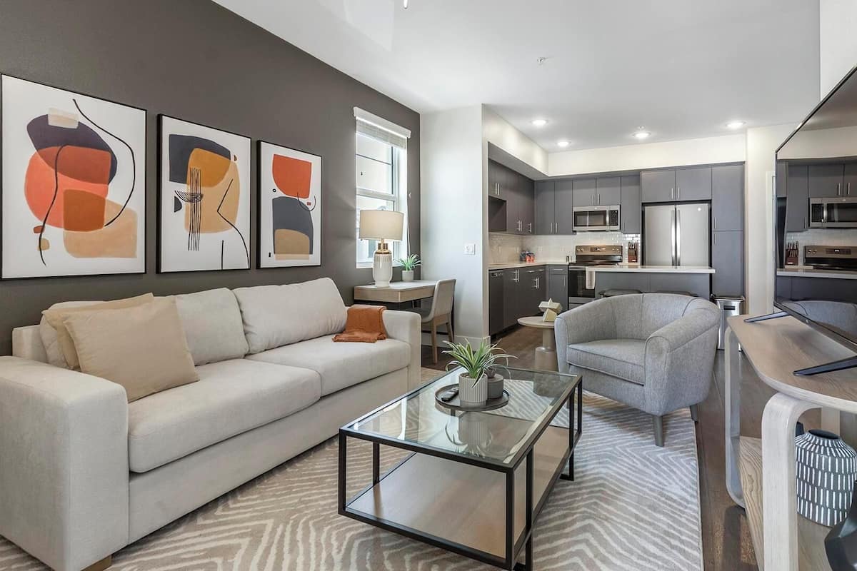 A modern living room with a sofa, armchair, coffee table, and abstract wall art.