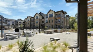 A courtyard with outdoor seating, a barbecue area, and a view of multi-story residential buildings. - Landing Apartments Charlotte near Bradfield Farms (Charlotte)