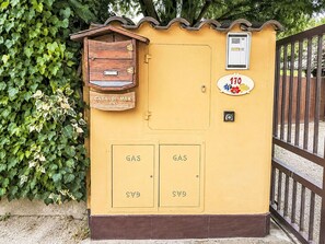 Ein gelber Verteilerkasten mit Briefkasten, Gasmeter und Hausnummer.
