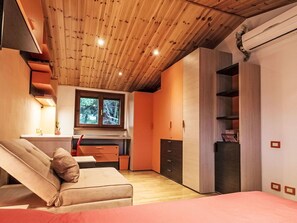 Ein modernes Schlafzimmer mit Holzboden, einem Sofa, einem Bett, einem Schreibtisch und einem Kleiderschrank.