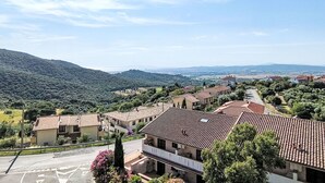 Zona residencial amb cases adossades, cel blau i un paisatge amb muntanyes al fons.