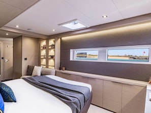 Une chambre dâhĂŽtel moderne Ă©quipĂ©e dâun lit, dâĂ©tagĂšres intĂ©grĂ©es, dâune tĂ©lĂ©vision et dâune fenĂȘtre donnant sur la plage.