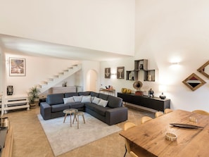 Ein modernes Wohnzimmer mit einem Ecksofa, einem Esstisch und einer Treppe.