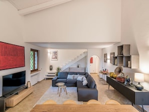 Ein modernes Wohnzimmer mit Ecksofa, Flachbildfernseher, einer Treppe und einer minimalistischen Einrichtung.