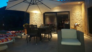 An outdoor patio with a dining table, chairs, a large umbrella, and a wicker sofa. - Quiet, modern villa with swimming pool 5 minutes' walk from the village (Tourrettes-sur-Loup)