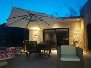 An outdoor patio with a dining table, chairs, a large umbrella, and a wicker sofa. - Quiet, modern villa with swimming pool 5 minutes' walk from the village (Tourrettes-sur-Loup)