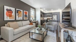 A modern living room with a sofa, armchair, coffee table, and abstract wall art. - Landing Amazing 1bd, Gym, Courtyard (Mobile)