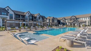 Une piscine avec des chaises longues, une pergola et des bâtiments modernes en arrière-plan.