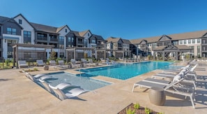 A swimming pool with lounge chairs, a pergola, and modern buildings in the background. - Landing Amazing 1bd, Gym, Courtyard (Mobile)
