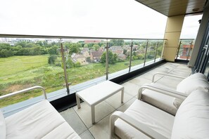 Un balcone con vista su una zona residenziale, un tavolino e due sedie bianche.