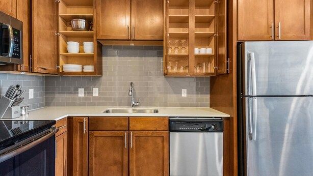 A modern kitchen with wooden cabinets, a stainless steel refrigerator, a dishwasher, and a microwave. - Landing Amazing 1BD in Northwest Side (San Antonio)