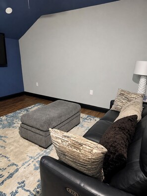 Una sala de estar con un sofá modular, un reposapiés y una alfombra estampada.