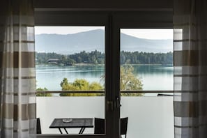 A room with a view of a lake and mountains, a table, and chairs. - Hotel Faaker See Inn by Aurora (Faak am See)