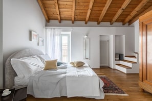 Ein Schlafzimmer mit einem Bett, Holzboden, einer Treppe und einer Tür.
