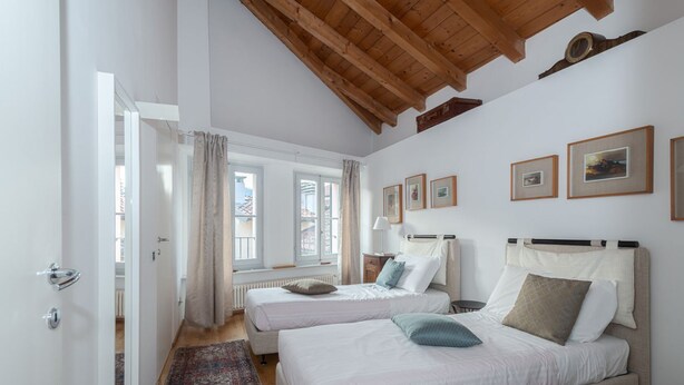 Ein Schlafzimmer mit zwei Betten, einer Holzbalkendecke und gerahmten Bildern an der Wand.