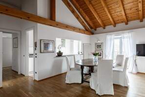 Ein Essbereich mit Holzbalkendecke, weißen Wänden und einem runden Tisch mit Stühlen.