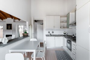 Eine moderne Küche mit weißen Schränken, einer Arbeitsplatte aus Granit und einem Essbereich mit weißen Stühlen.