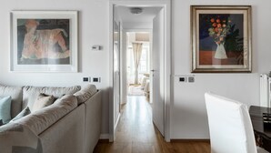 Ein Flur mit einer Couch, gerahmten Kunstwerken und einem Sessel.