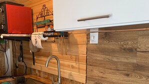 Eine Küche mit einer Holz Arbeitsplatte, einem Edelstahl-Spülbecken, einem roten Gerät und einem Herd.