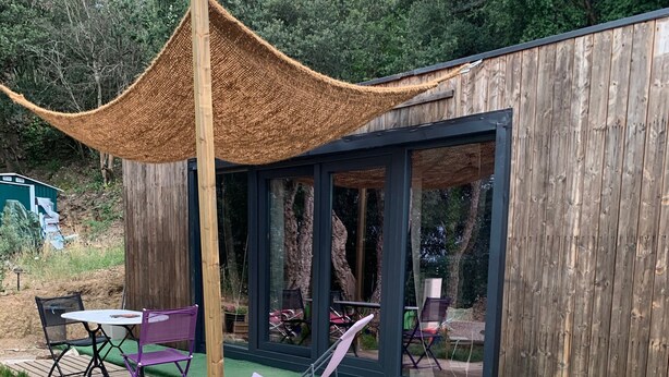 Ein moderner Außenbereich mit einer Holzterrasse, einer Pergola und einem gläsernen Anbau.