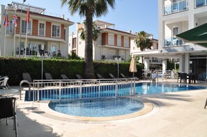 Una piscina amb indicador de profunditat de 30 cm, gandules i un edifici amb balcons.