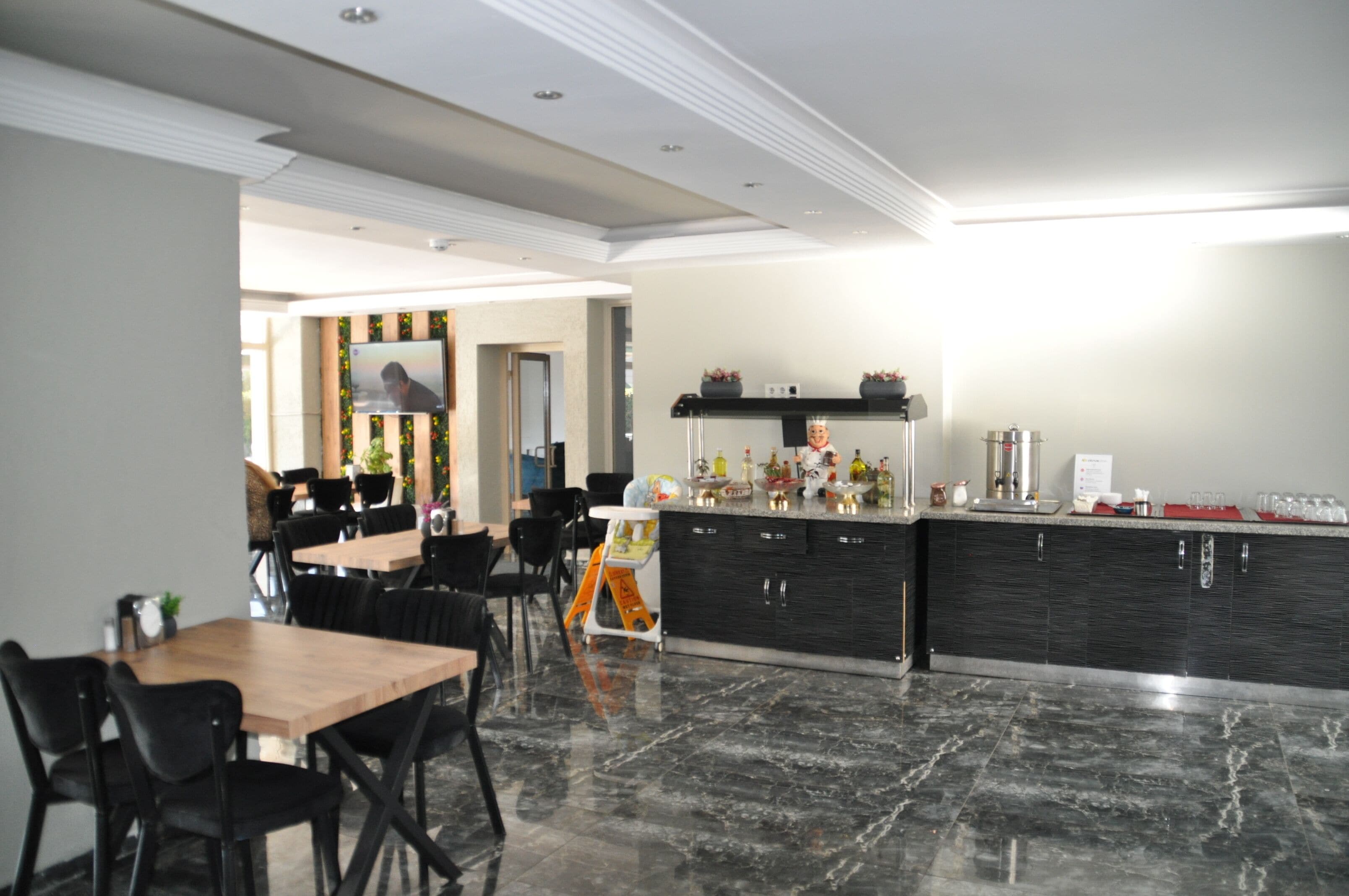 Une cuisine moderne dotée d’un plan de travail en marbre, de meubles noirs et d’un coin repas avec des chaises noires et une table en bois.