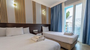 A hotel room with two beds, a wooden headboard, a nightstand, and a view of the outside. - Citrus Urban (Konyaaltı)
