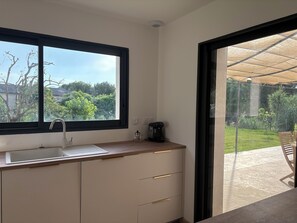 A modern kitchen with a window, a coffee machine, and a view of a garden. - NEW 2026:COMFORTABLE AIR-CONDITIONED HOUSE, PRIVATE POOL, CLOSE TO THE  VILLAGE (Sablet)