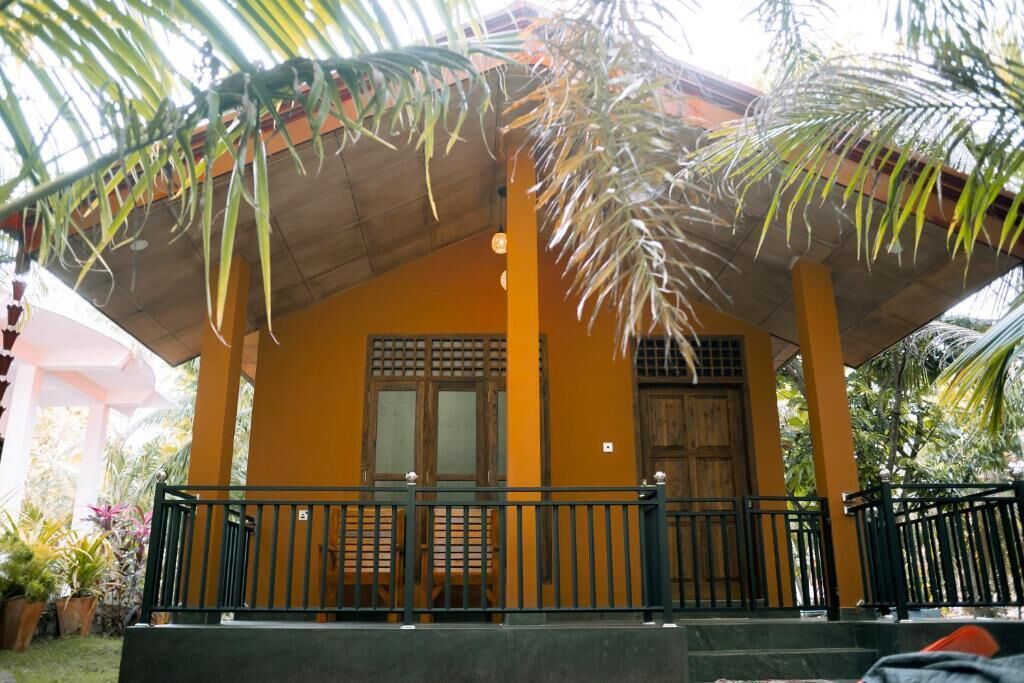 A yellow building with a covered porch, a wooden door, and a small window.